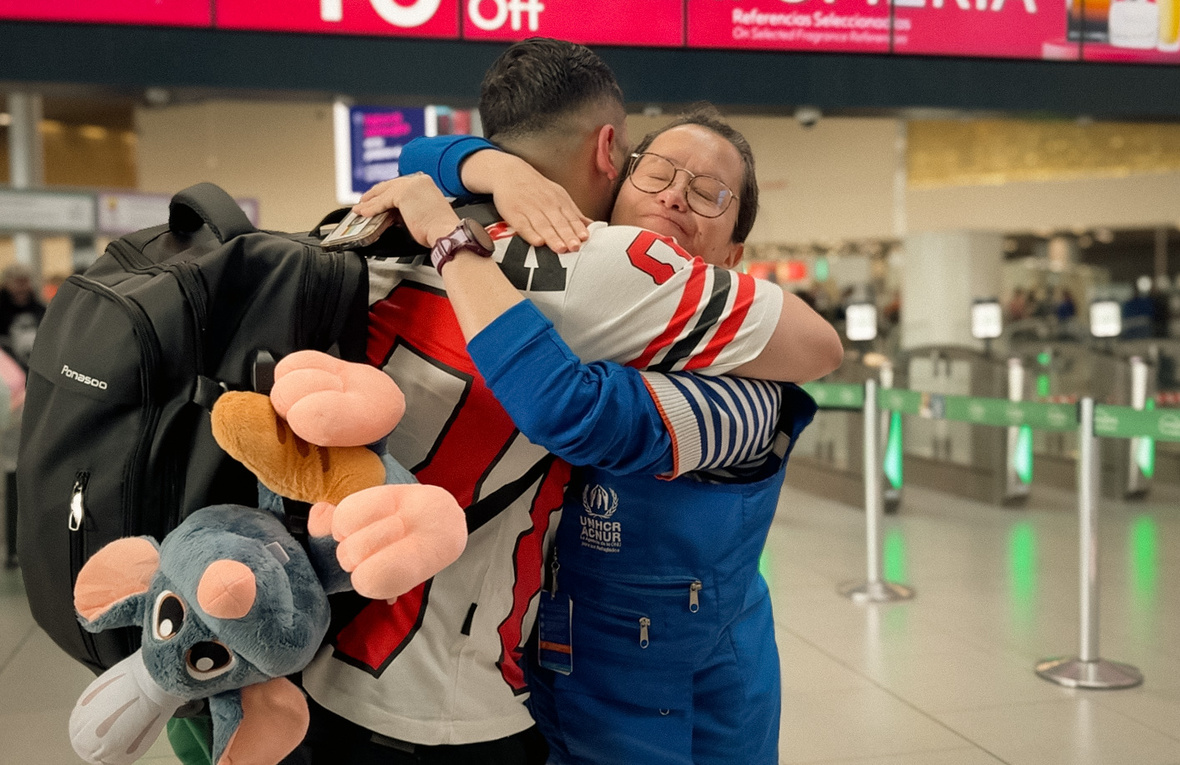 Un hombre se despide de una mujer con un abrazo en un aeropuerto.
