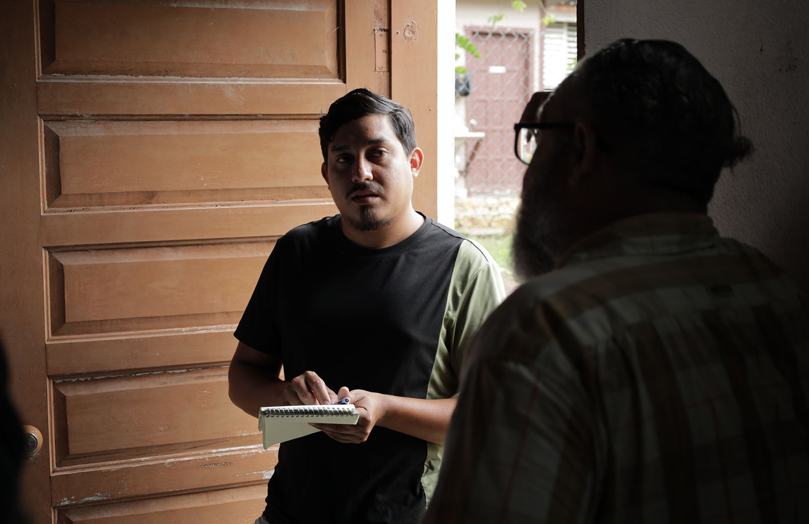 Dos hombres hablando en la entrada de una casa.