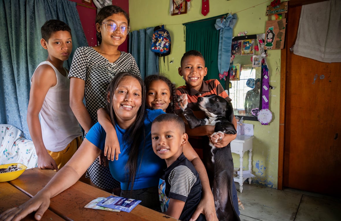Una mujer con sus cinco hijos alrededor de una mesa en su casa