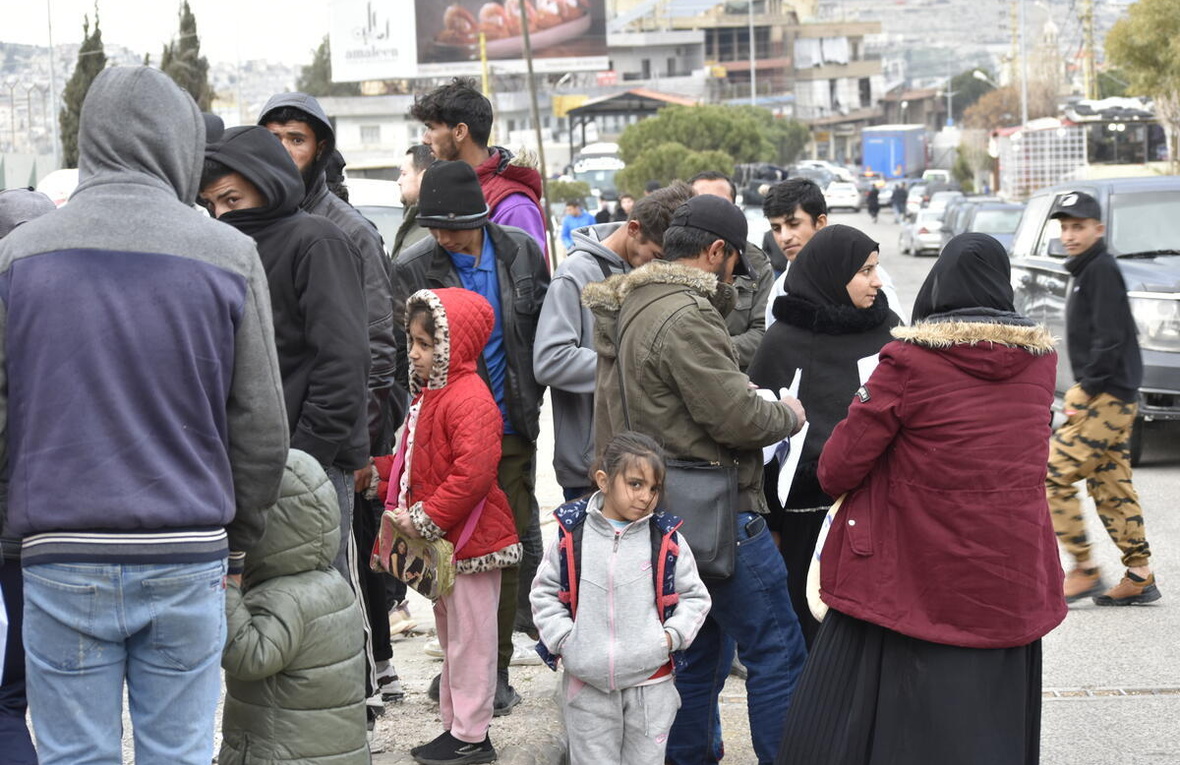 Un grupo de personas se reúnen en el paso fronterizo de Masnaa, en el Líbano, mientras espera cruzar a Siria para escapar de los bombardeos israelíes en curso y de las órdenes de evacuación.