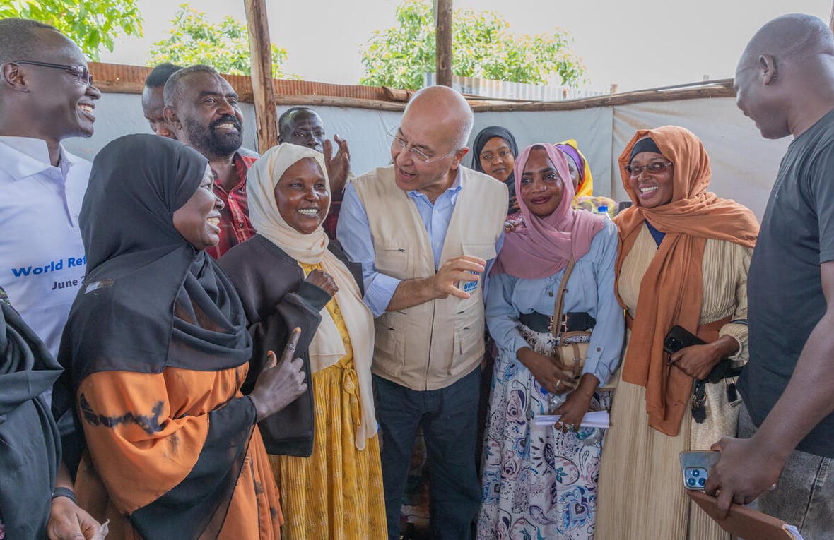 Un grupo de mujeres y hombres, con el Alto Comisionado de las Naciones Unidas para los Refugiados, Barham Salih, en el centro, conversa sonriendo. 