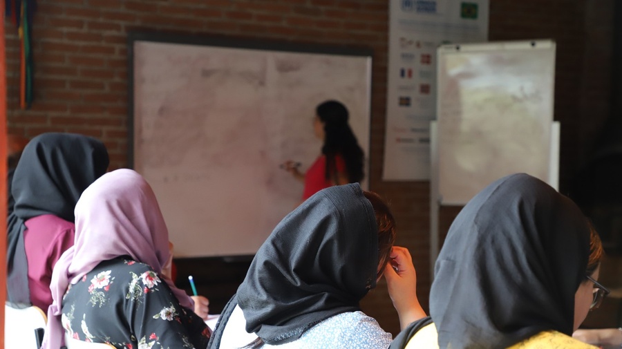 Un grupo de mujeres fotografiadas de espaldas asiste a una clase.