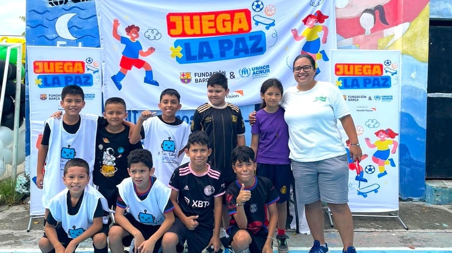 Un grupo de ocho niños, una niña y una mujer adulta con uniformes deportivos