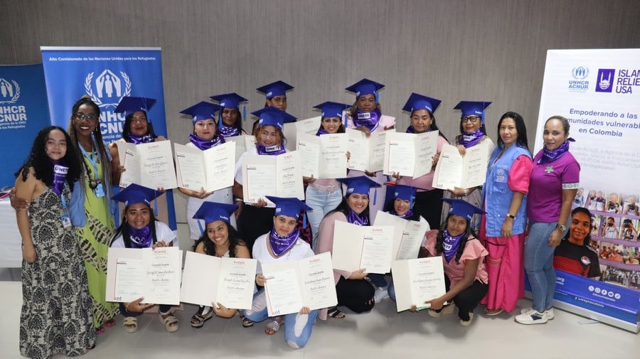 Un grupo de estudiantes recién graduados posa mostrando sus diplomas.
