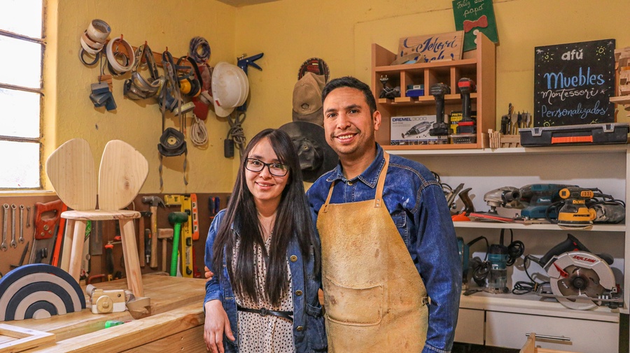 Un hombre y una mujer jóvenes de pie en un taller de carpintería