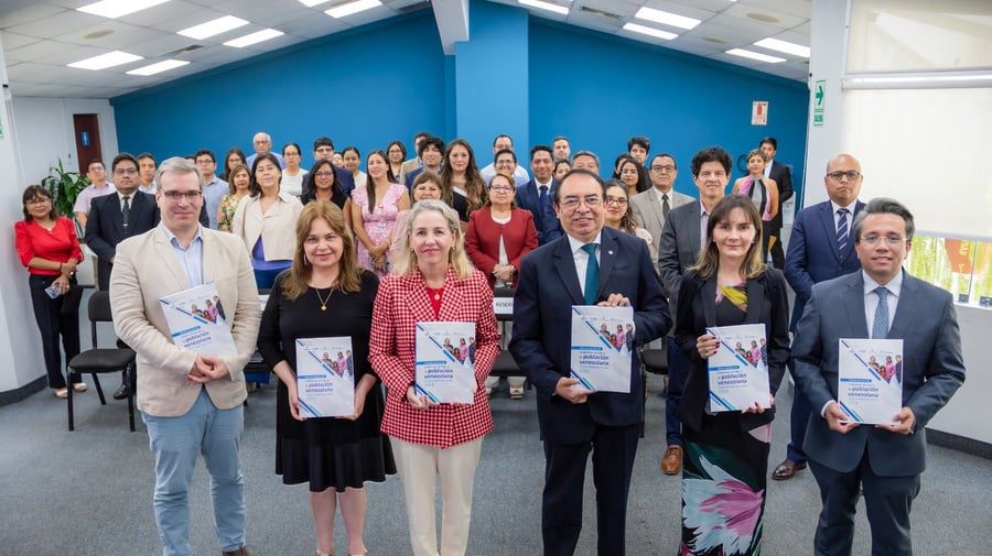 En primer plano tres hombres y tres mujeres que sostienen documentos en sus manos, en segundo plano, un grupo de alrededor de 50 personas posan también para la foto