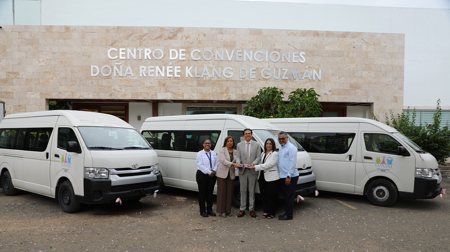 Tre hombres y dos mujeres posan para la foto con tres camionetas blancas al fondo