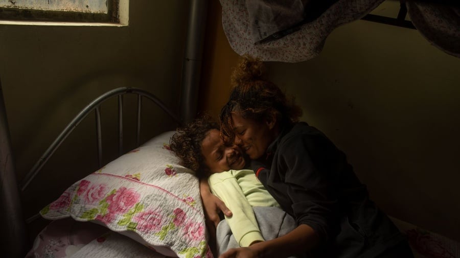 Una mujer abraza a un niño antes de dormir.