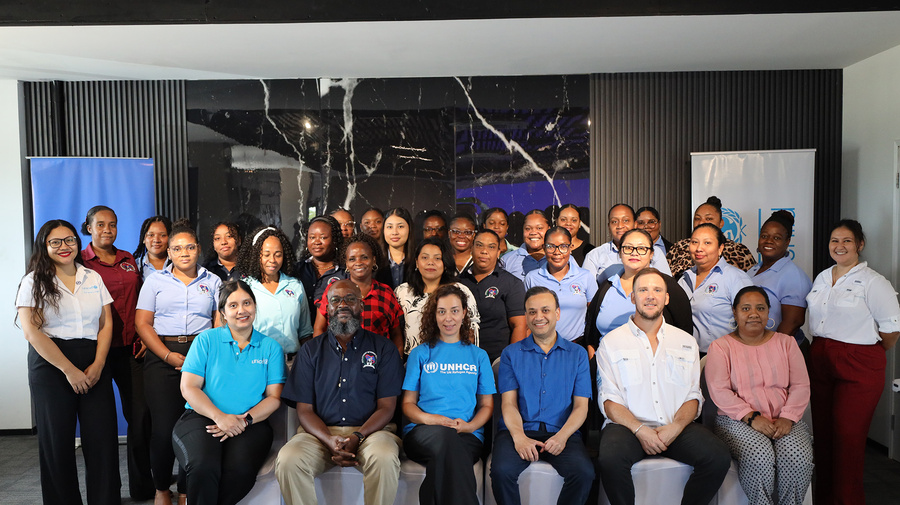 A group of 30 people posing for a photo in a conference room
