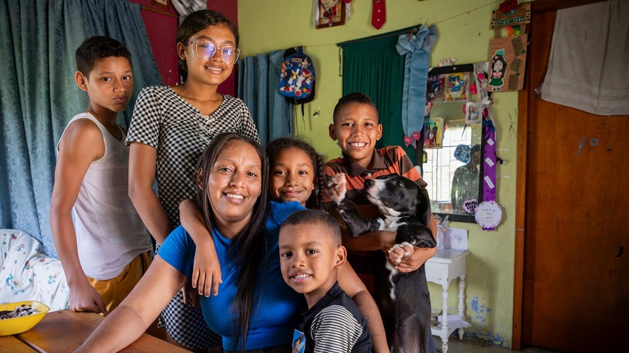 Una mujer con sus cinco hijos alrededor de una mesa en su casa
