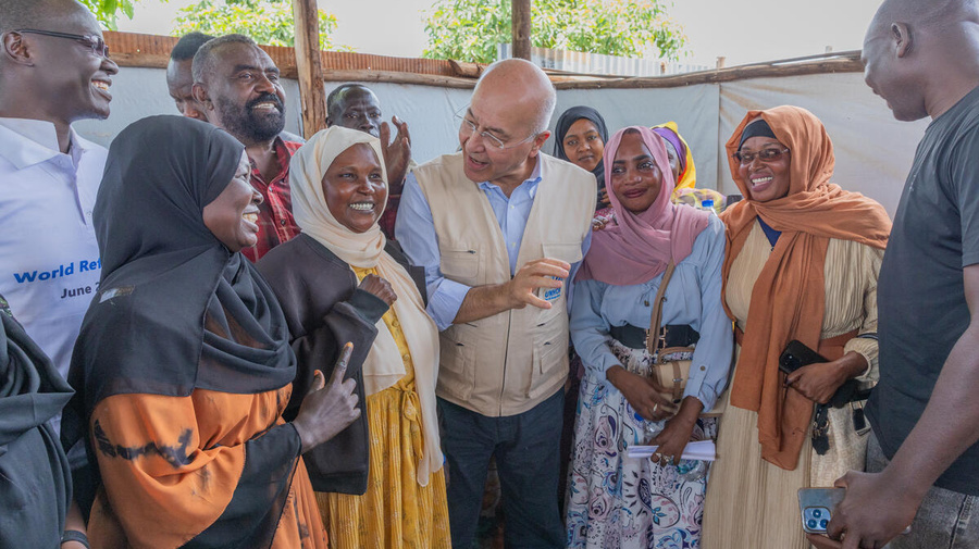 Un grupo de mujeres y hombres, con el Alto Comisionado de las Naciones Unidas para los Refugiados, Barham Salih, en el centro, conversa sonriendo. 