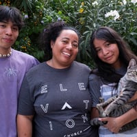 Al centro, una mujer con su hija y su hijo adolescentes. Su hija, quienestá a su lado izquierdo, sostiene entre sus brazos a un gato
