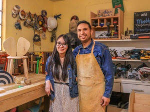 Un hombre y una mujer jóvenes de pie en un taller de carpintería