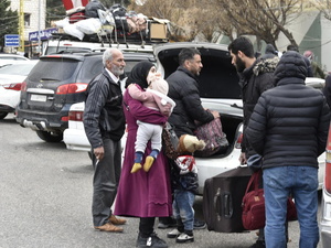 Personas reunidas detrás de un automóvil estacionado en el paso fronterizo de Masnaa, en Líbano, esperando para cruzar a Siria.