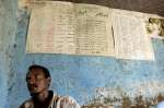 Un refugiado eritreo espera para hacer una llamada en una oficina telefónica en el campamento de refugiados de Kilo 26. En la pared detrás de él están las tarifas de las llamadas para países de todo el mundo. 