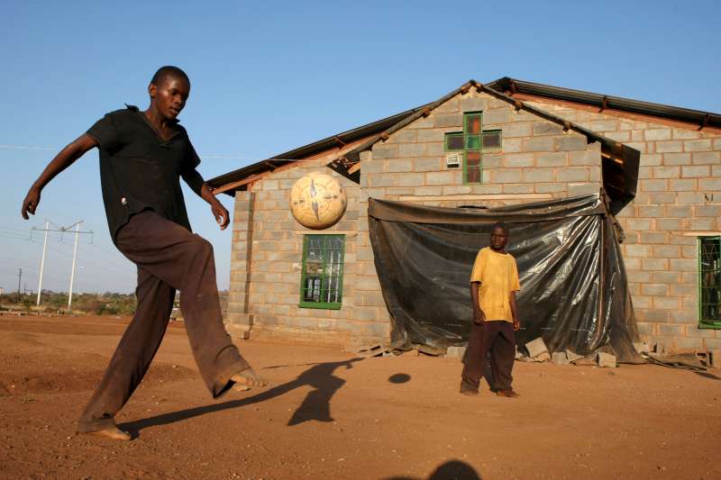 El adolescente Conwell juega fútbol en el refugio de niños en Nancefield, Musina, Sudáfrica. El refugio alberga a más de 200 niños de hasta 16 años. La mayoría de los niños cruzaron la frontera sin compañía. Se les da comida, alojamiento y educación.