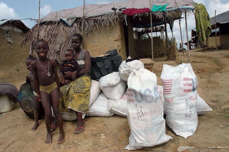 Una familia liberiana desplazada internamente espera abordar el camión que los llevará a casa después de la distribución de ayuda en el campamento de desplazados internos de Salala, Gbarnga