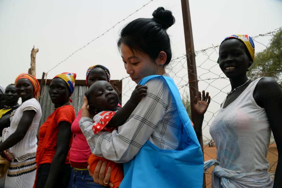 La trabajadora de ACNUR Eujin Byun cargando en sus brazos a un bebé refugiados en un campamento en Sudán del Sur.  