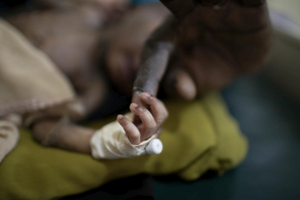Un refugiados recién nacido toma el dedo del Dr. Evan Atar Adaha en la sala de maternidad del Hospital Bunj en Sudán del Sur. 