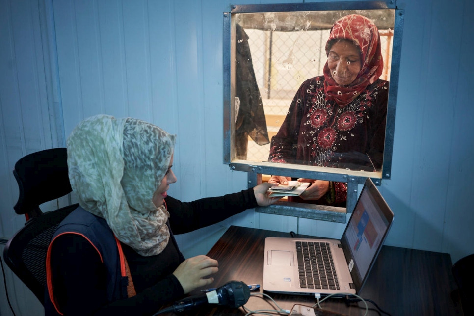 Refugiados sirios hacen cola para recibir la asistencia en efectivo de invierno en el campamento de refugiados de Zaatari, en Jordania, en noviembre de 2017. La ayuda permite a los refugiados pagar el suministro de calefacción o comprar materiales aislantes y ropa de abrigo.  