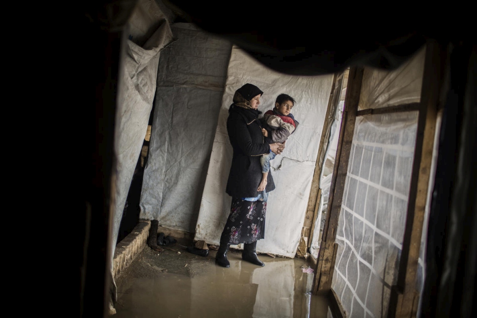 Juriya Ramadan carga a uno de sus hijos mientras revisa su casa inundada en el asentamiento informal Dalhamiya en el Valle de la Becá, Líbano  