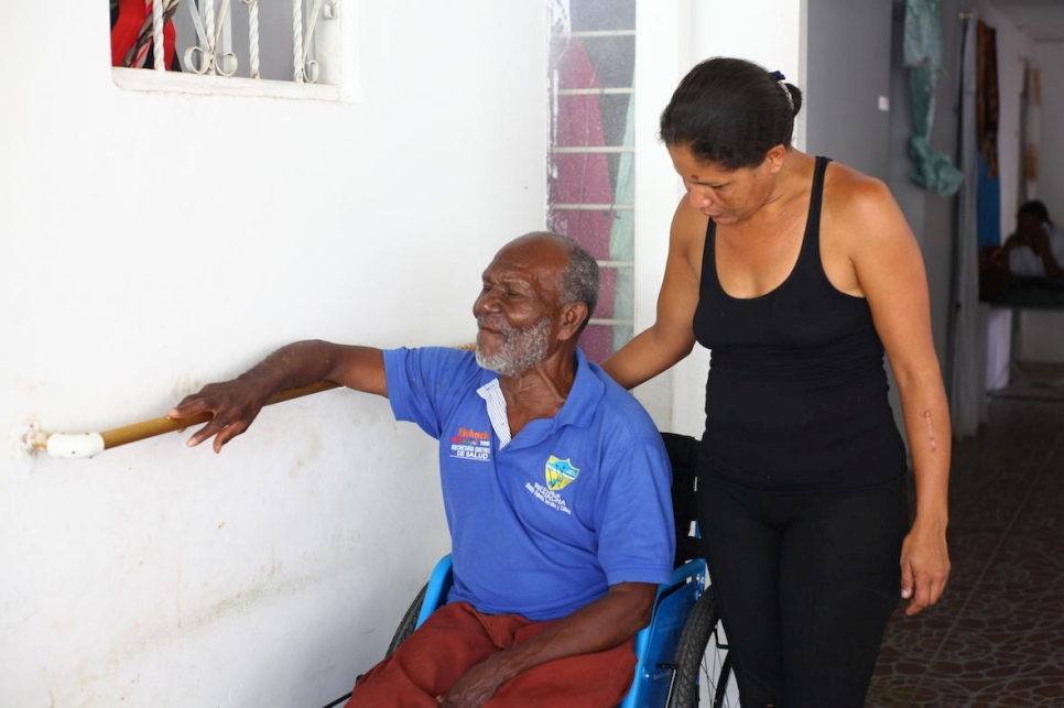 Una mujer venezolana ayuda a un hombre colombiano en silla de ruedas en la Casa del abuelo en Riohacha, Colombia.