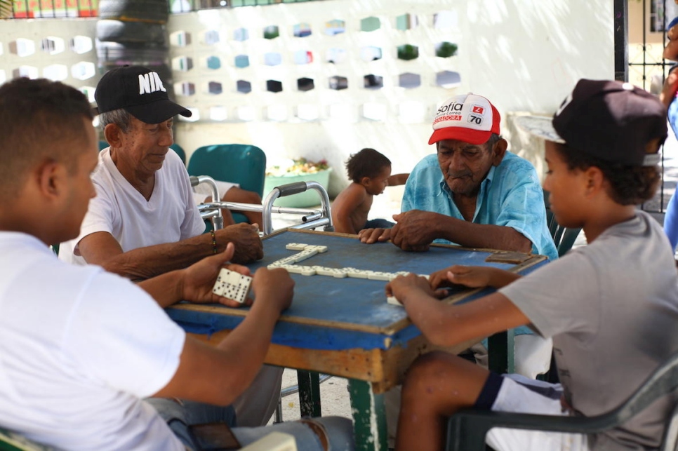 Adultos mayores colombianos y jóvenes venezolanos juegan dominó en la Casa del Abuelo en Riohacha, en el norte de Colombia. 