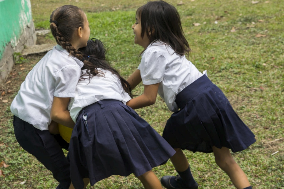 Estudiantes nicaragüenses y costarricenses juegan juntas fuera de su escuela. 