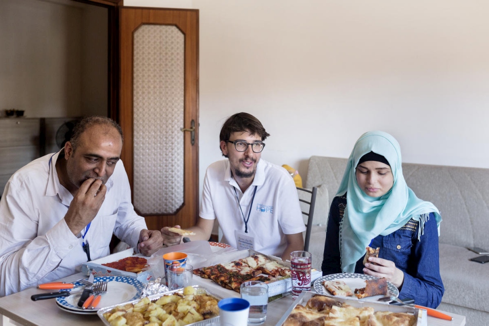 Simone Scotta (centro), de la Federación Italiana de Iglesias Evangélicas, come pizza con Ammar Issa, de 48 años, y Sara, de 16, refugiados palestinos de Siria recién llegados a Roma desde el Líbano. 