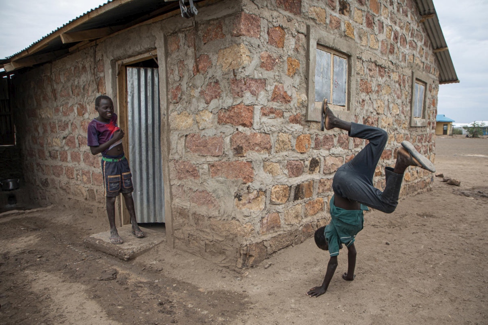 El refugiado sursudanés Luiz Ohisa, de 12 años, juega fuera de su hogar de reciente construcción en el asentamiento de Kalobeyei (Kenia) bajo la atenta mirada de su hermano.  