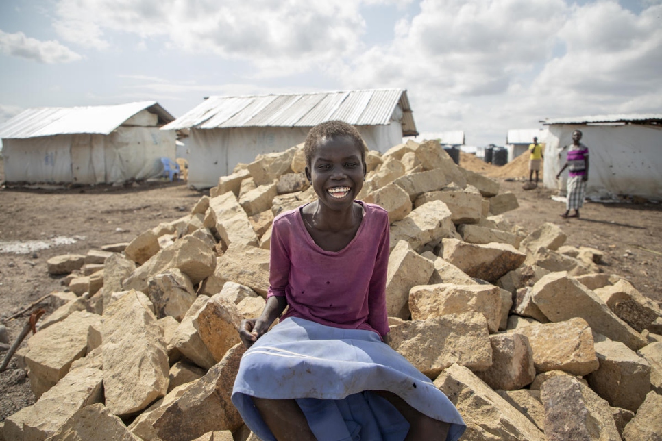 Betty Dikun, refugiada procedente de Fajalik (Sudán del Sur), sentada sobre un montón de piedras que se van a utilizar para construir un hogar para su familia como parte del proyecto de ayudas en efectivo para construir viviendas en el asentamiento de Kalobeyei.  