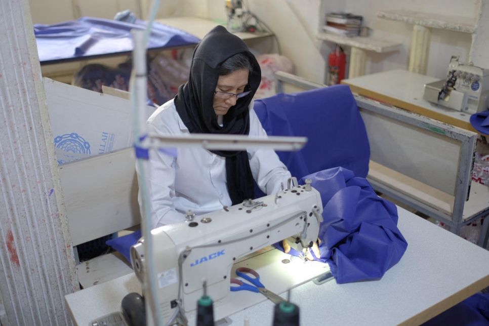 La refugiada afgana Mahroo, de 40 años, hace batas de hospital en el taller de confección. 