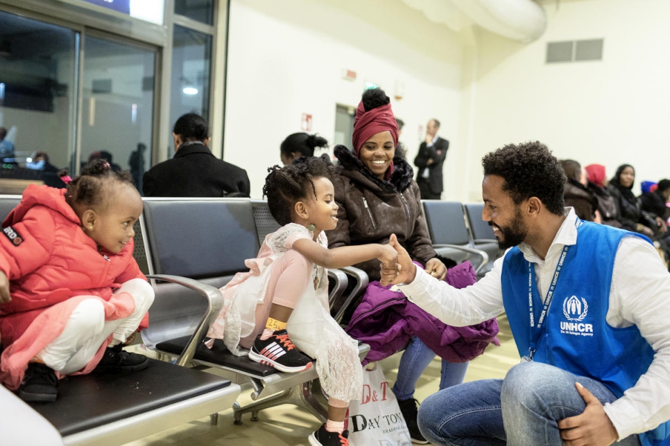 Dawit America Girmay, un mediador cultural de ACNUR, entretiene a una niña eritrea recién llegada a Roma, Italia, en un vuelo de reubicación desde Níger.