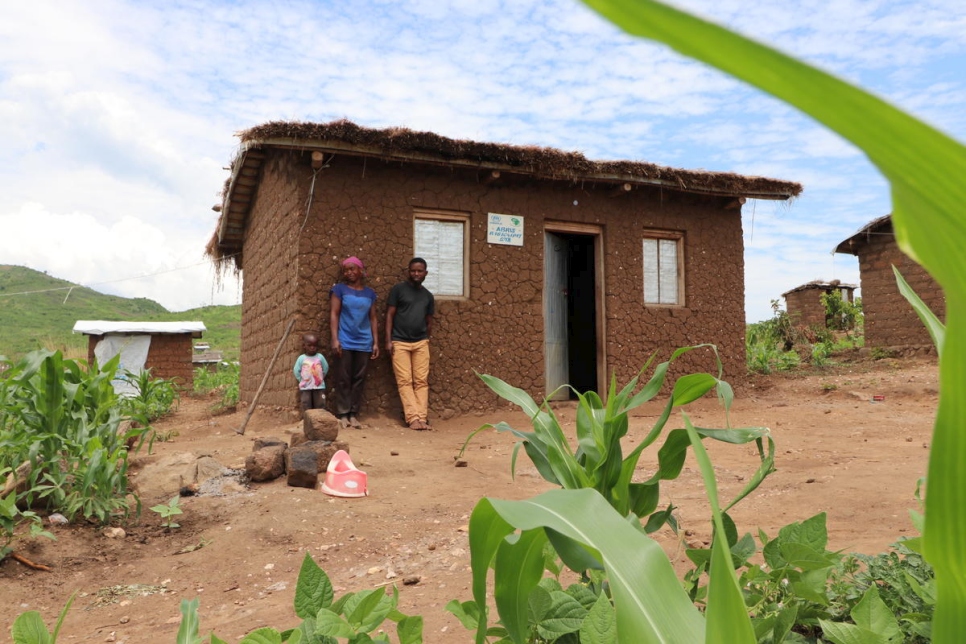 La refugiada burundesa Aisha, su hijo y su marido Matias posan ante su vivienda en el asentamiento de Mulongwe (República Democrática del Congo). 