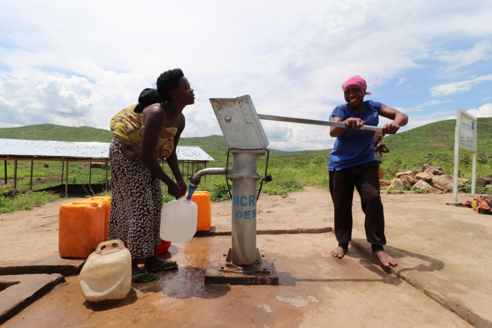 Aisha (der.) extrae agua de un pozo perforado en el asentamiento de Mulongwe (República Democrática del Congo). 