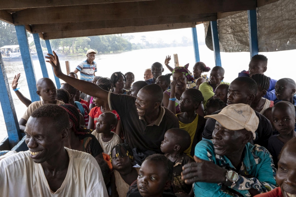 Repatriados voluntarios saludan cuando la barca que los lleva de vuelta a la República Centroafricana abandona el puerto de Zongo (República Democrática del Congo) el pasado 21 de noviembre.