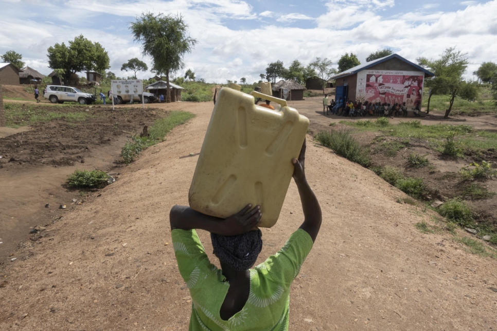 La refugiada sursudanesa Asha Rose Sillah transporta un bidón de agua desde una fuente hasta su hogar en el campamento de refugiados de Bidibidi (Uganda). 