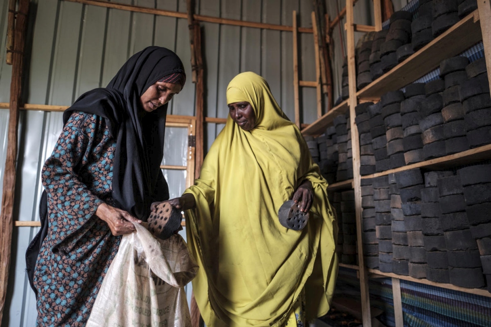 La refugiada somalí Asha Abdikadir Ahmed (izquierda), de 42 años, compra briquetas de carbón en el Centro de Procesamiento de Prosopis en Bur Amino, Etiopía. 