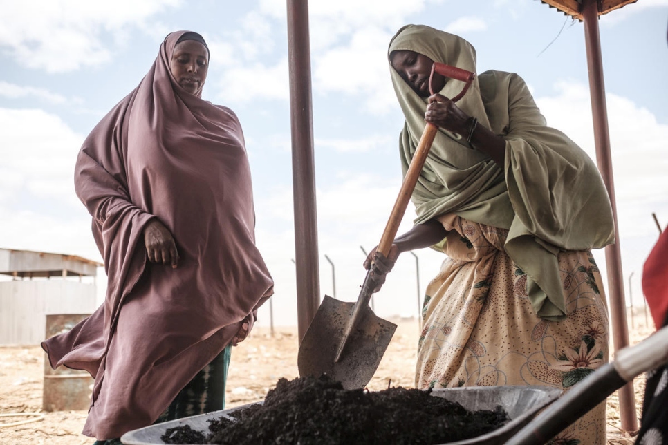 La refugiada somalí Saredo Abdi, de 26 años, (derecha) mueve el carbón con una pala en el Centro de Procesamiento de Prosopis en Bur Amino, Etiopía. 