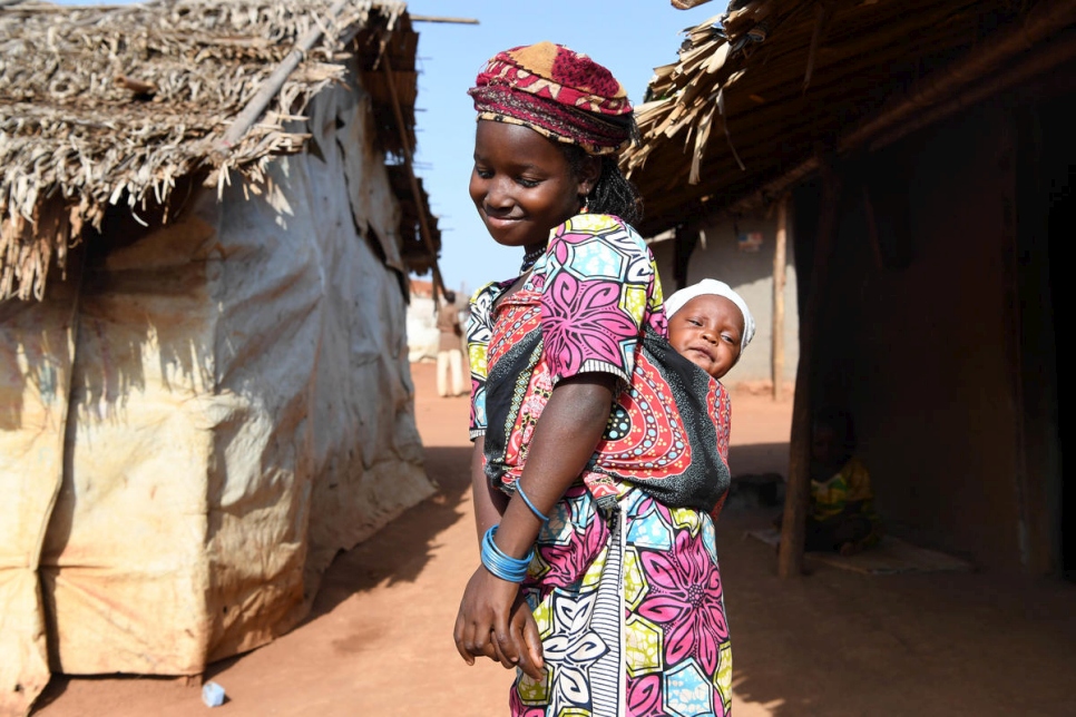 Una niña carga a su hermano pequeño sobre su espalda en el campamento de refugiados de Mbile, uno de los varios sitios en la Región Este donde el método madre cangura está salvando la vida de los bebés prematuros. 
