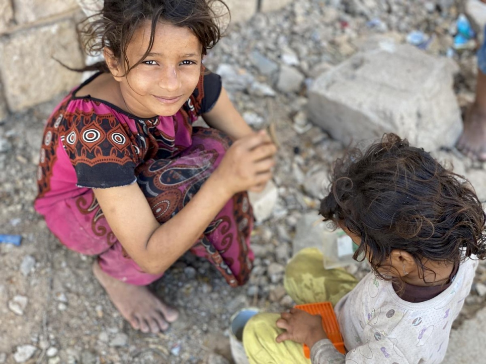 Ipteehal, de 9 años, juega con su hermana fuera del edificio inacabado donde viven con otras familias desplazadas en Al Mukalla, Yemen. 