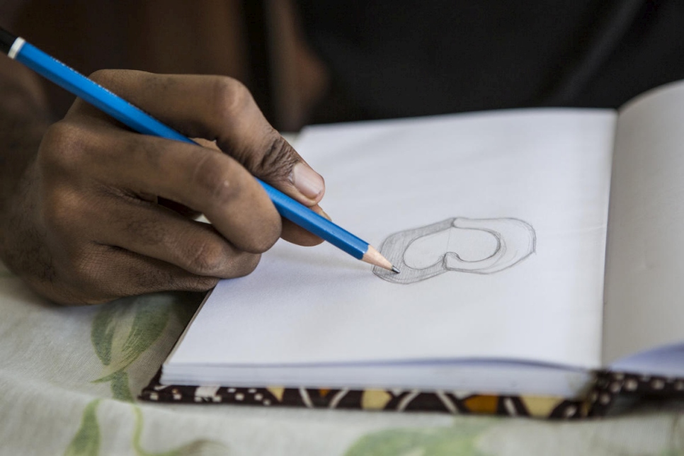 El diseñador gráfico marfileño O'Plérou dibuja en papel el diseño del emoji del Día Mundial del Refugiado 2020 antes de pasar a la computadora. 