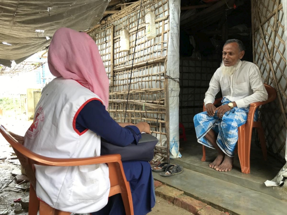 Una refugiada rohingya capacitada como trabajadora comunitaria de salud visita un hogar en su comunidad para concienciar sobre la COVID-19.
