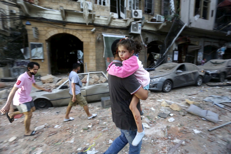 Un hombre lleva a una niña herida a un lugar seguro tras la explosión masiva en el puerto de Beirut, El Líbano.