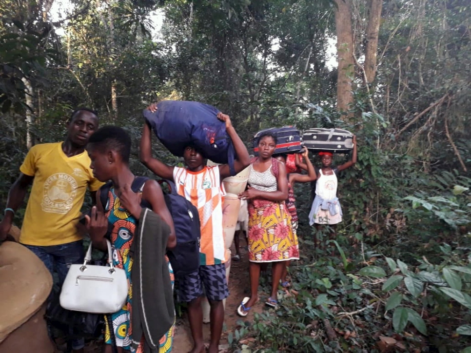 Hombres, mujeres y niños se desplazan a pie en el bosque cargando sus pertenencias.