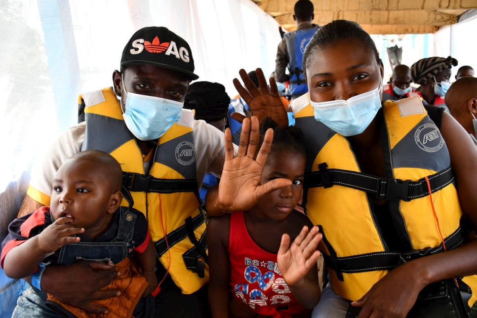 Retornados centroafricanos saludan mientras el bote que los está llevando de vuelta a su país zarpa de Zongo, en la República Democrática del Congo, en noviembre de 2020.