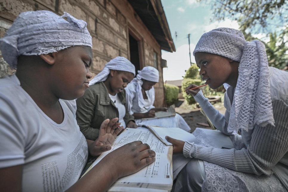 La mujer apátrida shona Nosizi Reuben (derecha) ayuda a sus hermanas, (de la izquierda) Janet, Tema y Brenda, en sus estudios, fuera de su casa en Kinoo, Kenia, en noviembre de 2020.