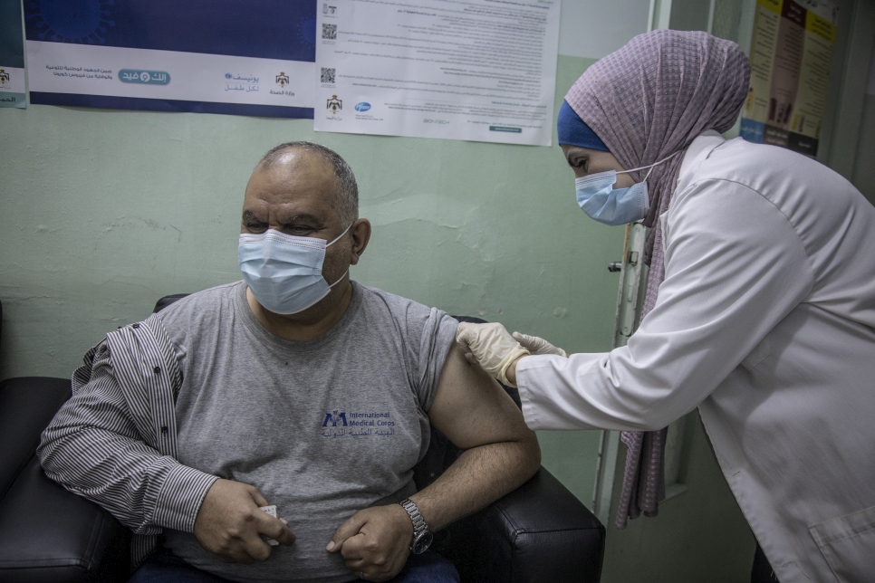 Trabajadores sanitarios administran la primera dosis de la vacuna COVID-19 a personas refugiadas en la Clínica de Vacunación de Irbid, en Jordania.  