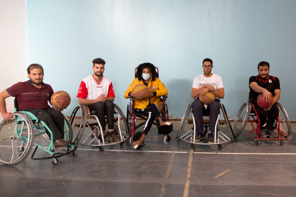 Mohamed (de amarillo) se toma una fotografía con otros usuarios de sillas de ruedas después de verlos jugar un partido de baloncesto.