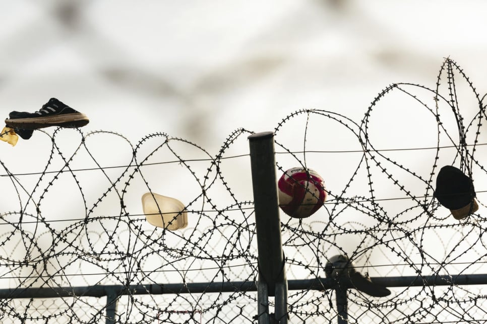 Zapatos, una pelota y un gorro atrapados en la valla de alambre en el centro de recepción e identificación de Fylakio, cerca de la frontera greco-turca